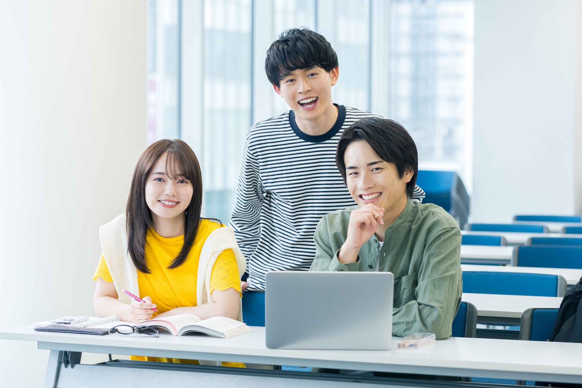 教室でノートパソコンを囲んで学ぶ学生たち